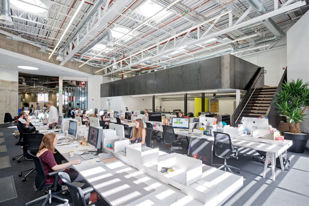 Workplace with people working at workstations with a mezzanine floor above
